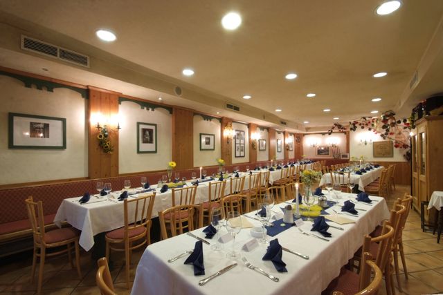 Eleganter Speisesaal mit gedeckten Tischen und blauen Servietten.