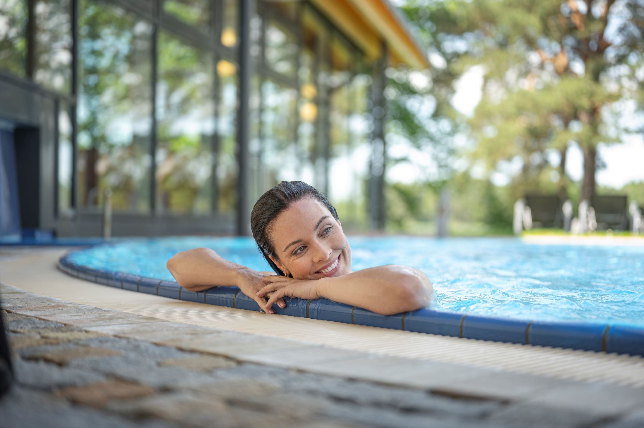 Frau entspannt im Pool am Beckenrand.