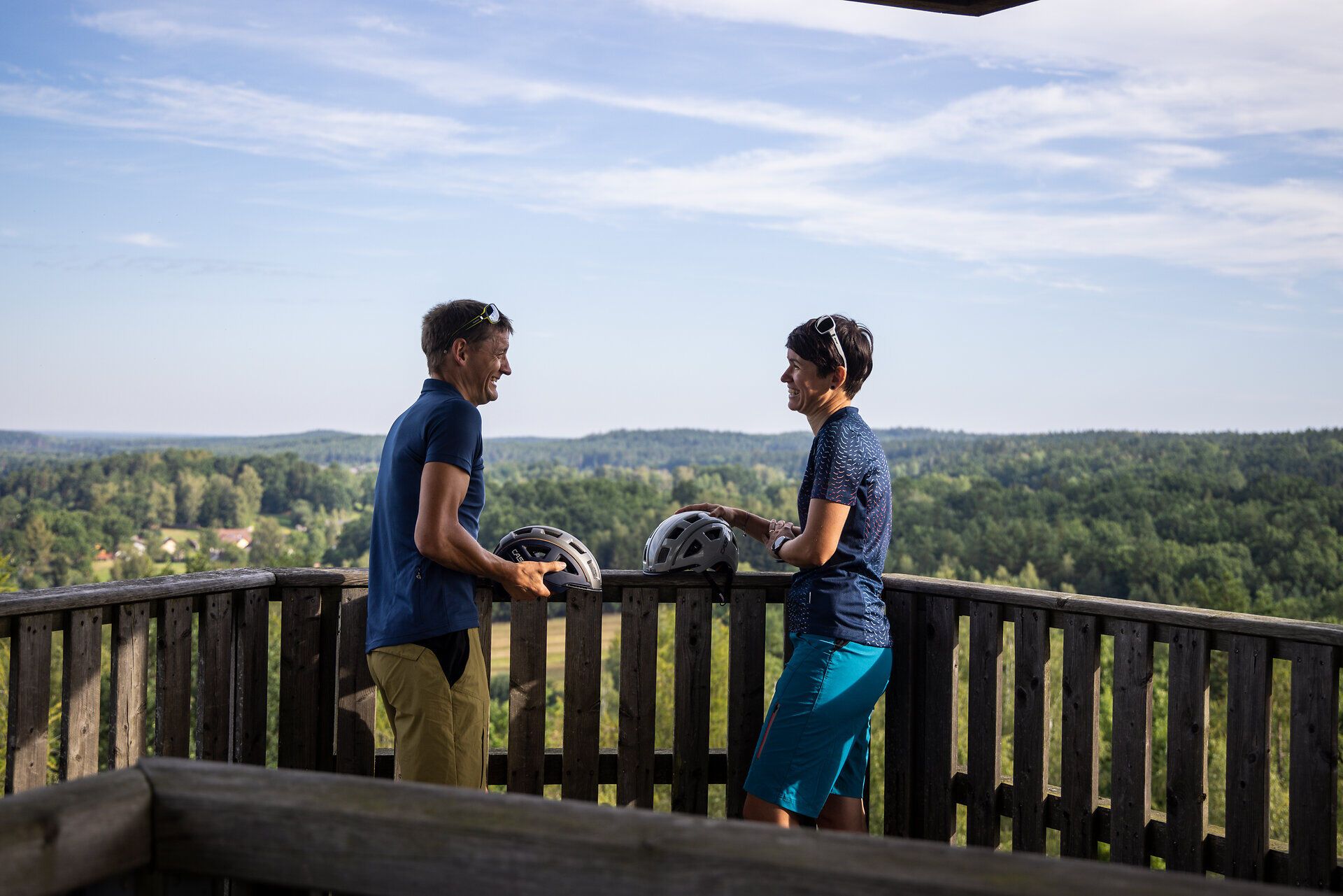 Inmitten der malerischen Landschaft des Naturparks Blockheide genießen zwei Radfahrer die frische Bergluft und den atemberaubenden Ausblick. Umgeben von üppigem Grün und sanften Hügeln, strahlt die Szenerie eine einladende Ruhe aus, die zum Verweilen und Entdecken einlädt.