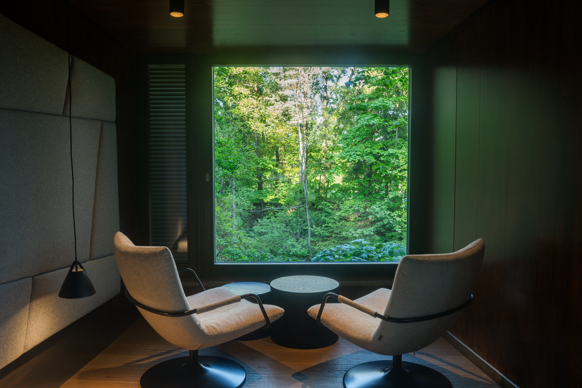 Interior view of a modern tree house with two armchairs and large window with forest view.