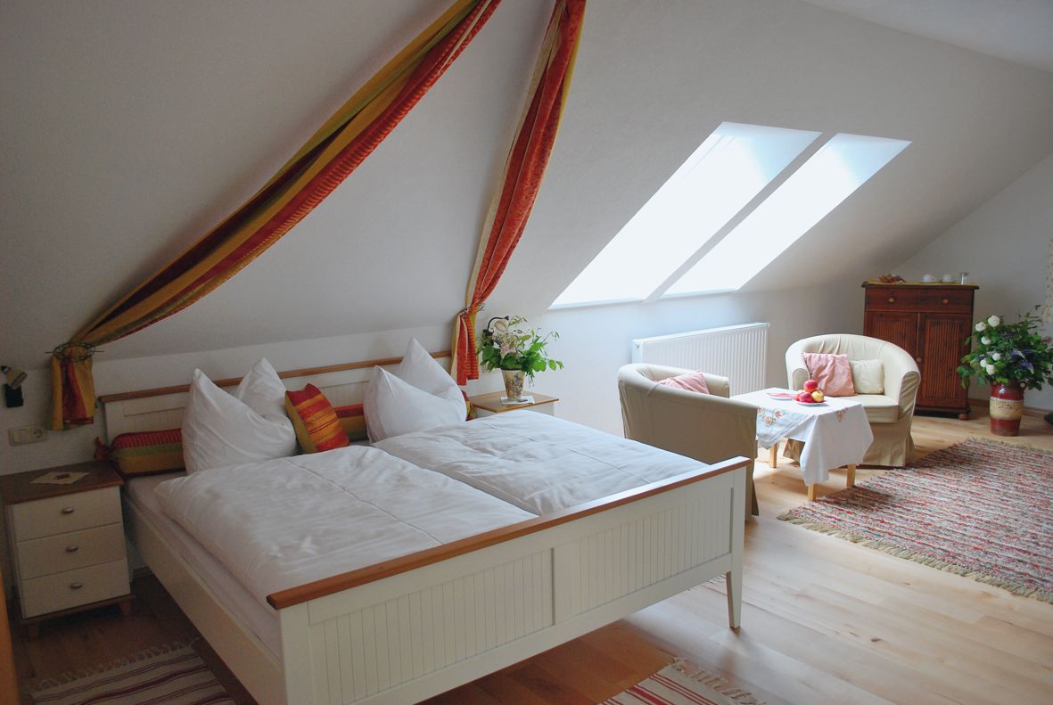 Gemütliches Schlafzimmer mit Doppelbett, Sesseln und Tisch unter Dachschräge.