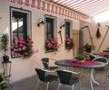 Gemütlicher Außenbereich eines Gasthauses mit Tischen, Stühlen und Blumen.