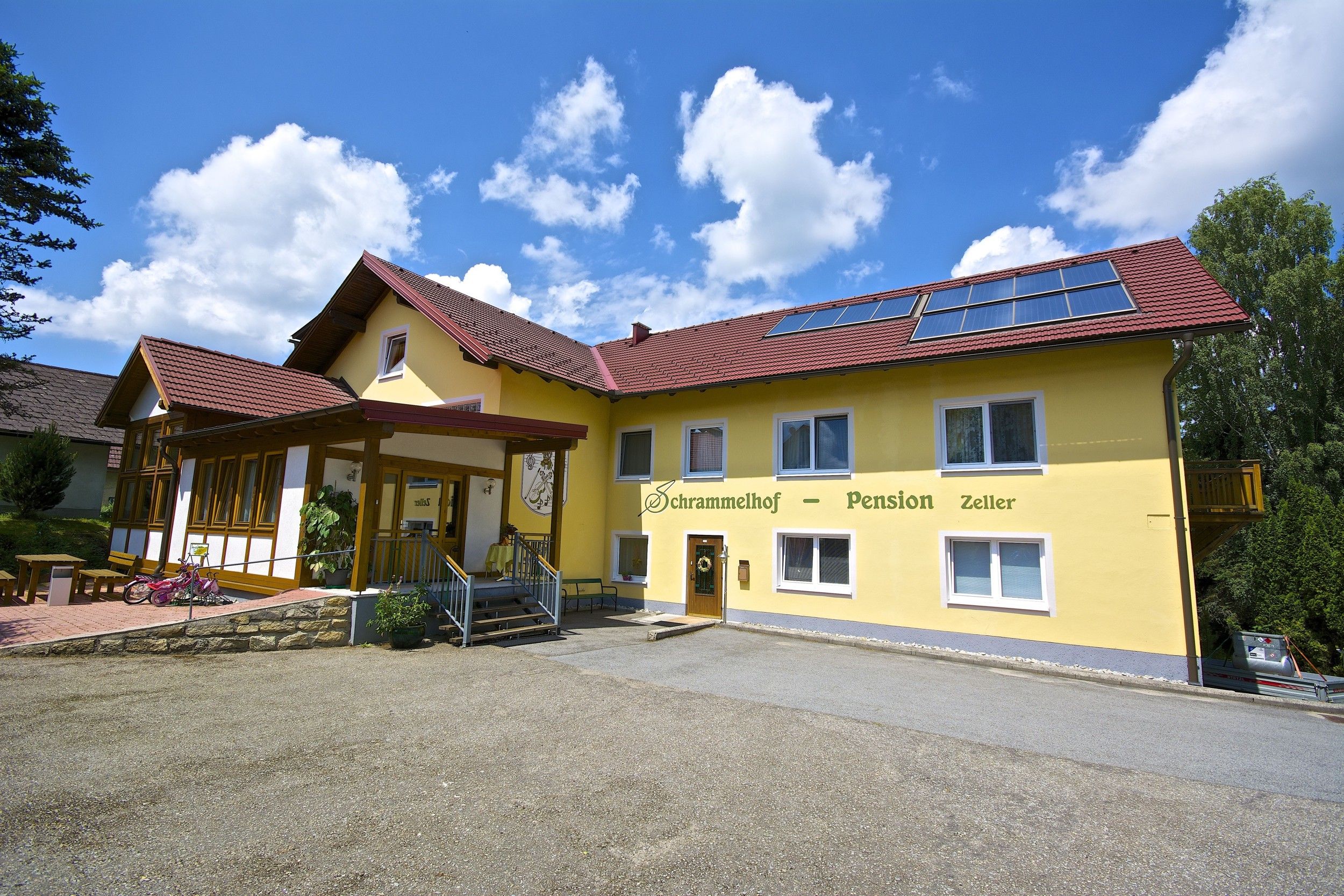 Gelbes Gebäude der Frühstückspension Schrammelhof mit Solarpanelen auf dem Dach.