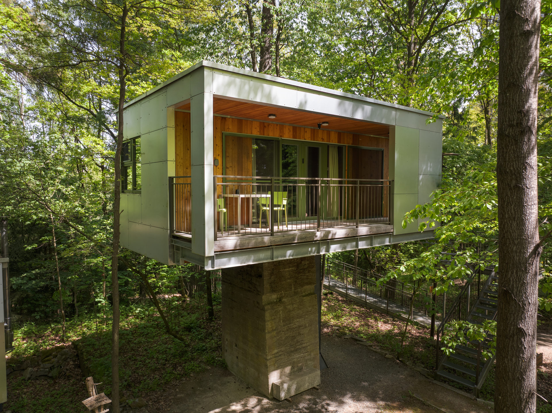 Modern tree house in the forest with balcony and glass front.