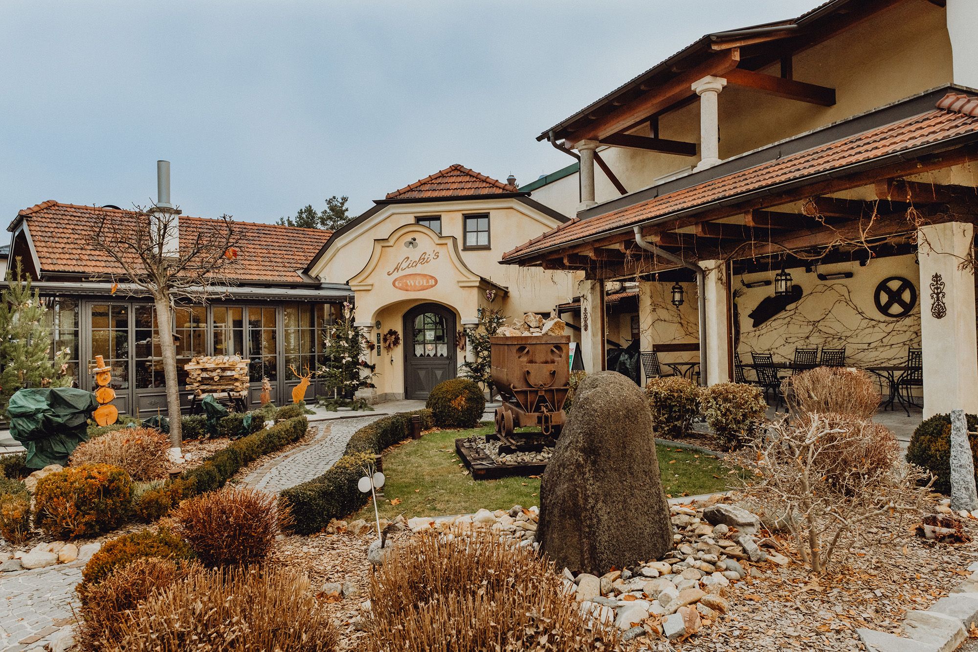 Außenansicht eines traditionellen Wirtshauses mit Garten und Dekorationen.